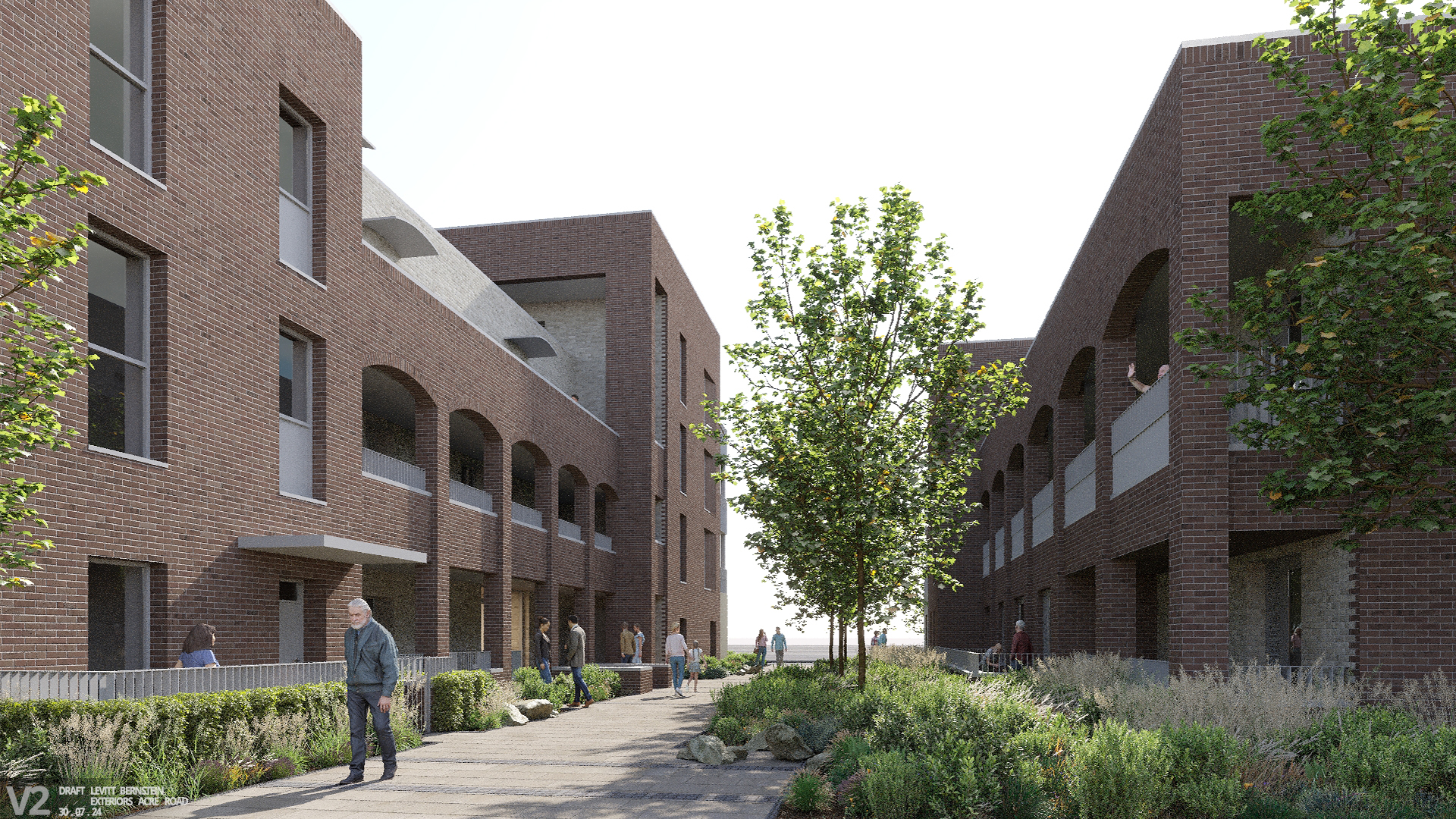 Image shows people walking on a paved pathway through grass, flowers and trees between two brick buildings with balconies.